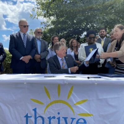 A group of people signing a document at a table.