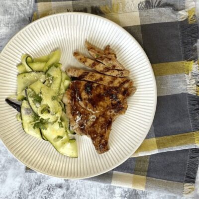 A plate with grilled pork chops and cucumbers.