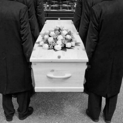 Black and white photo of men carrying a casket.