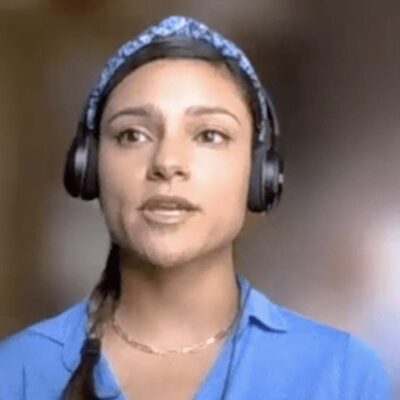 A woman in a blue shirt is wearing headphones.