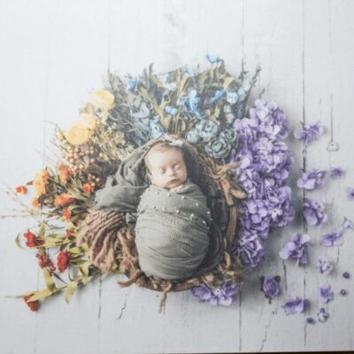 A baby is laying in a nest of flowers.