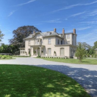 A large mansion in the middle of a green lawn.