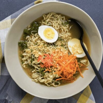 A bowl of ramen with an egg and vegetables.
