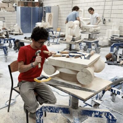 A group of people working on a sculpture in a workshop.