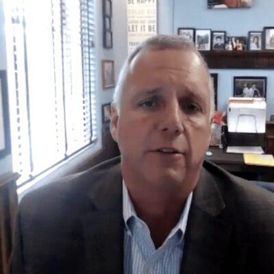 A man in a suit sitting in front of a desk.