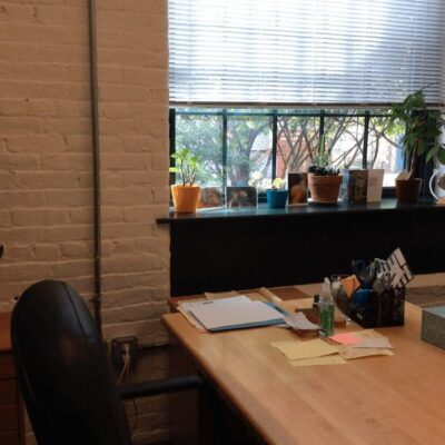A wooden desk in a room with a window.