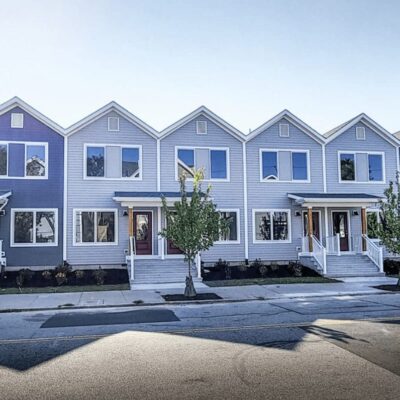 A row of blue townhouses on a street.