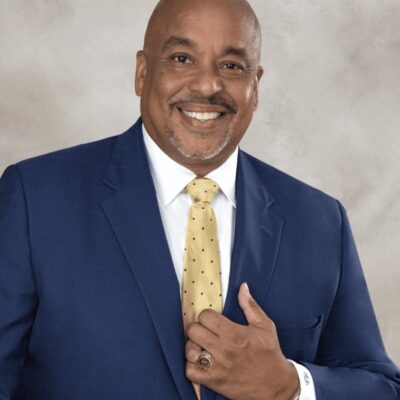 A black man in a suit and tie smiling.