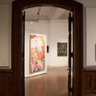 A room with paintings on the wall and a doorway.