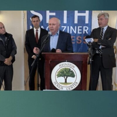 A man is standing at a podium with three men behind him.