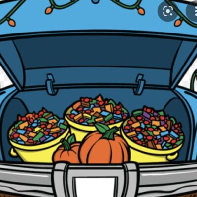 A blue truck with pumpkins and candy in the back.