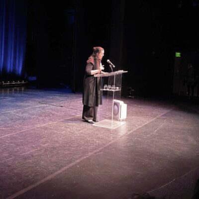 A woman standing at a podium in front of an audience.