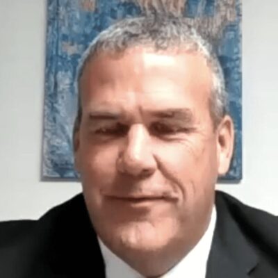A man in a suit and tie sitting in front of a desk.