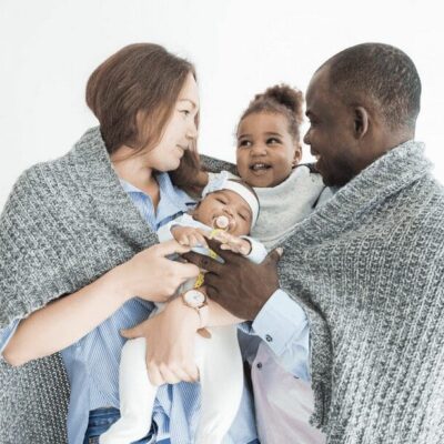 A family holding a baby wrapped in a blanket.