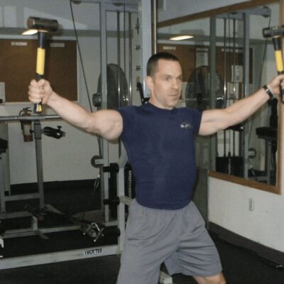 A man in a gym holding a pair of dumbbells.