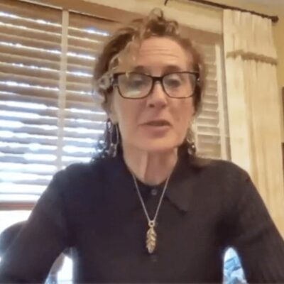 A woman wearing glasses is sitting at a table.