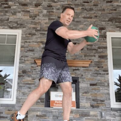 A man is doing a squat with a green ball.