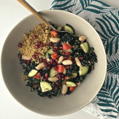 A bowl of kale and pomegranate salad with pomegranate seeds.