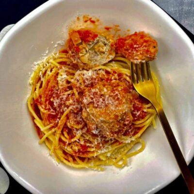 A white plate with spaghetti and meatballs on it.