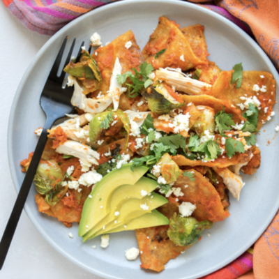 A plate of nachos with chicken and avocado on it.