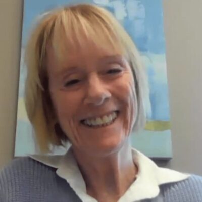 A woman smiling in front of a painting.