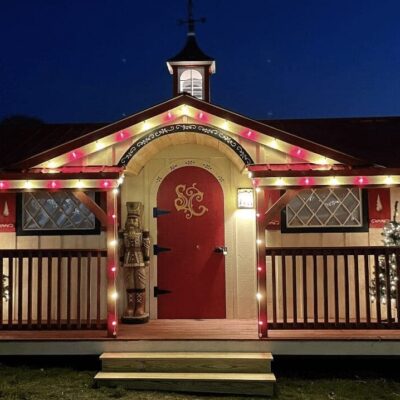 A red and white cottage with lights on the front porch.