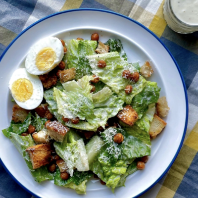 A plate of caesar salad with croutons and hard boiled egg.