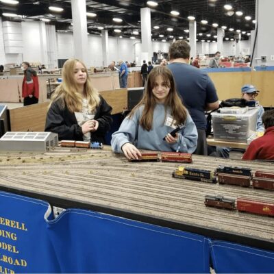A group of people looking at model trains at a convention.