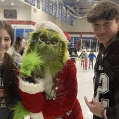 A group of people posing with a santa claus mascot.