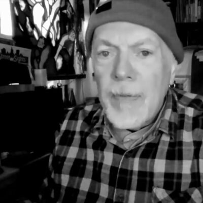 A black and white photo of a man in a plaid shirt.