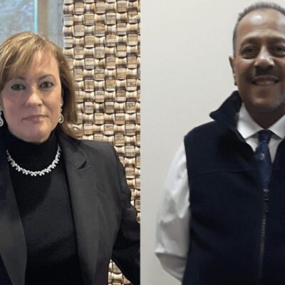 Two people standing next to each other in front of a wall.