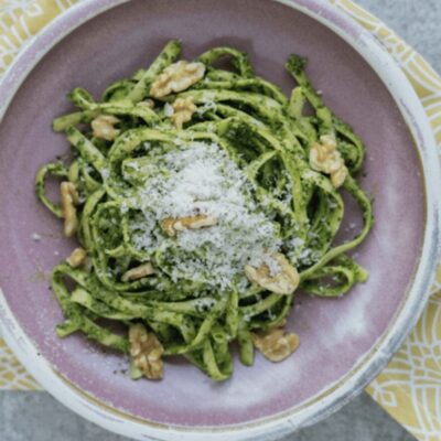 A bowl of pesto pasta with walnuts and parmesan.