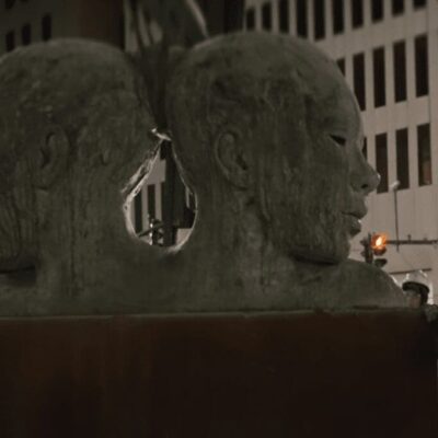 A statue of two heads in the middle of a street.