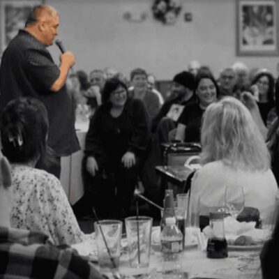 A black and white photo of a man standing in front of a crowd.