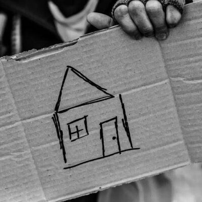A person holding up a cardboard box with a drawing of a house.