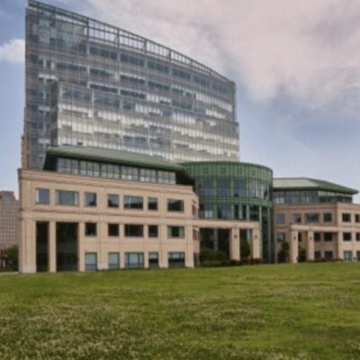 A grassy field with tall buildings in the background.