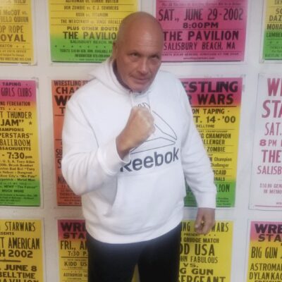 A bald man standing in front of a wall full of posters.