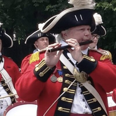 A group of men in red uniforms playing flutes.
