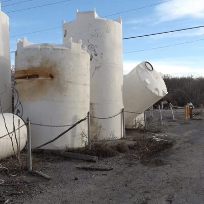 A group of white tanks on the side of a road.