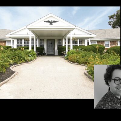 A woman in glasses is standing in front of a building.