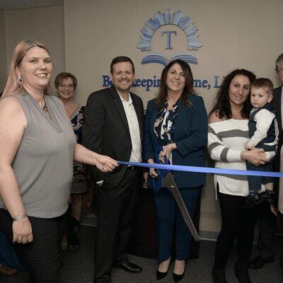 A group of people cutting a ribbon at a ribbon cutting ceremony.