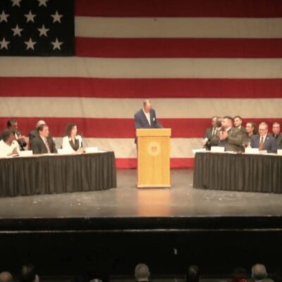 A group of people sitting at a table in front of an american flag.