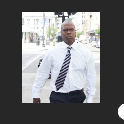 A man in a white shirt and tie walking down the street.