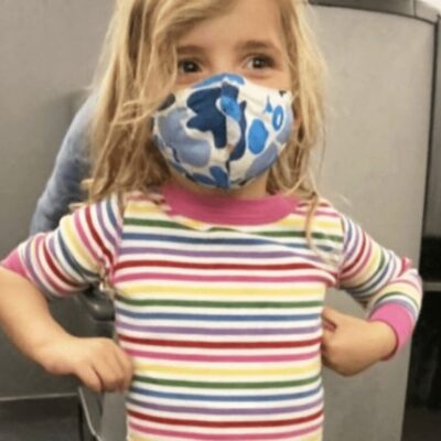 A little girl wearing a face mask in an airport.