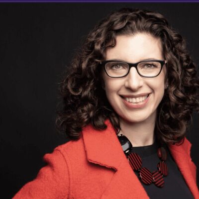 An image of a woman wearing glasses and a red jacket.