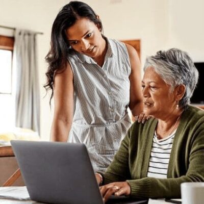 A woman is working on a laptop with an older woman.