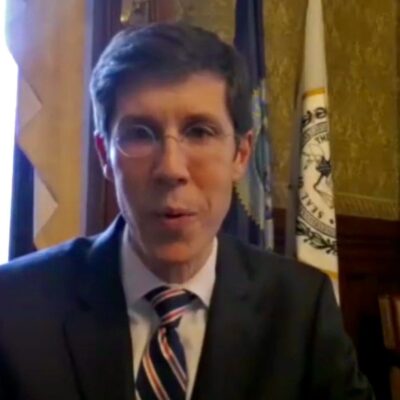 A man in a suit and tie is talking to the camera.