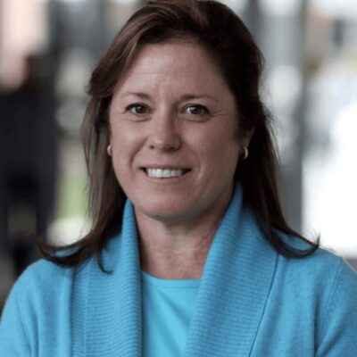 A woman in a blue sweater smiles for the camera.