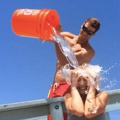 A man is splashing a woman with a bucket of water.