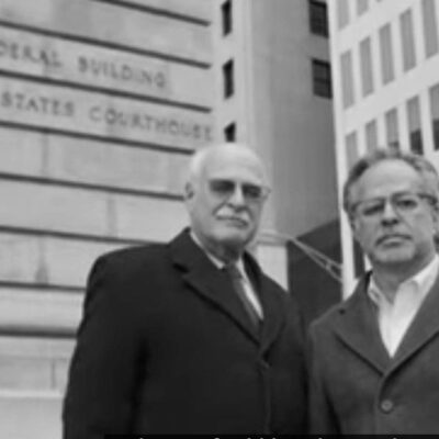 Two men in suits standing in front of a building.